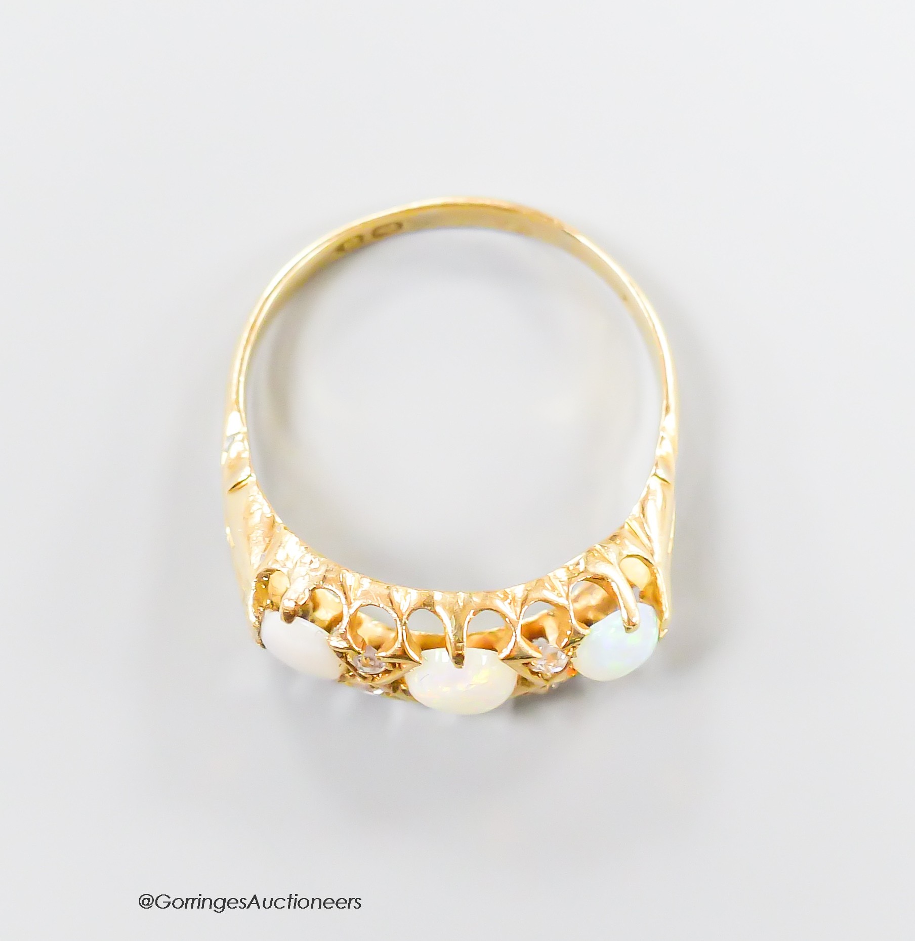 An Edwardian yellow metal, three stone opal and four stone diamond chip set half hoop ring, size Q/R, gross 3.5 grams.